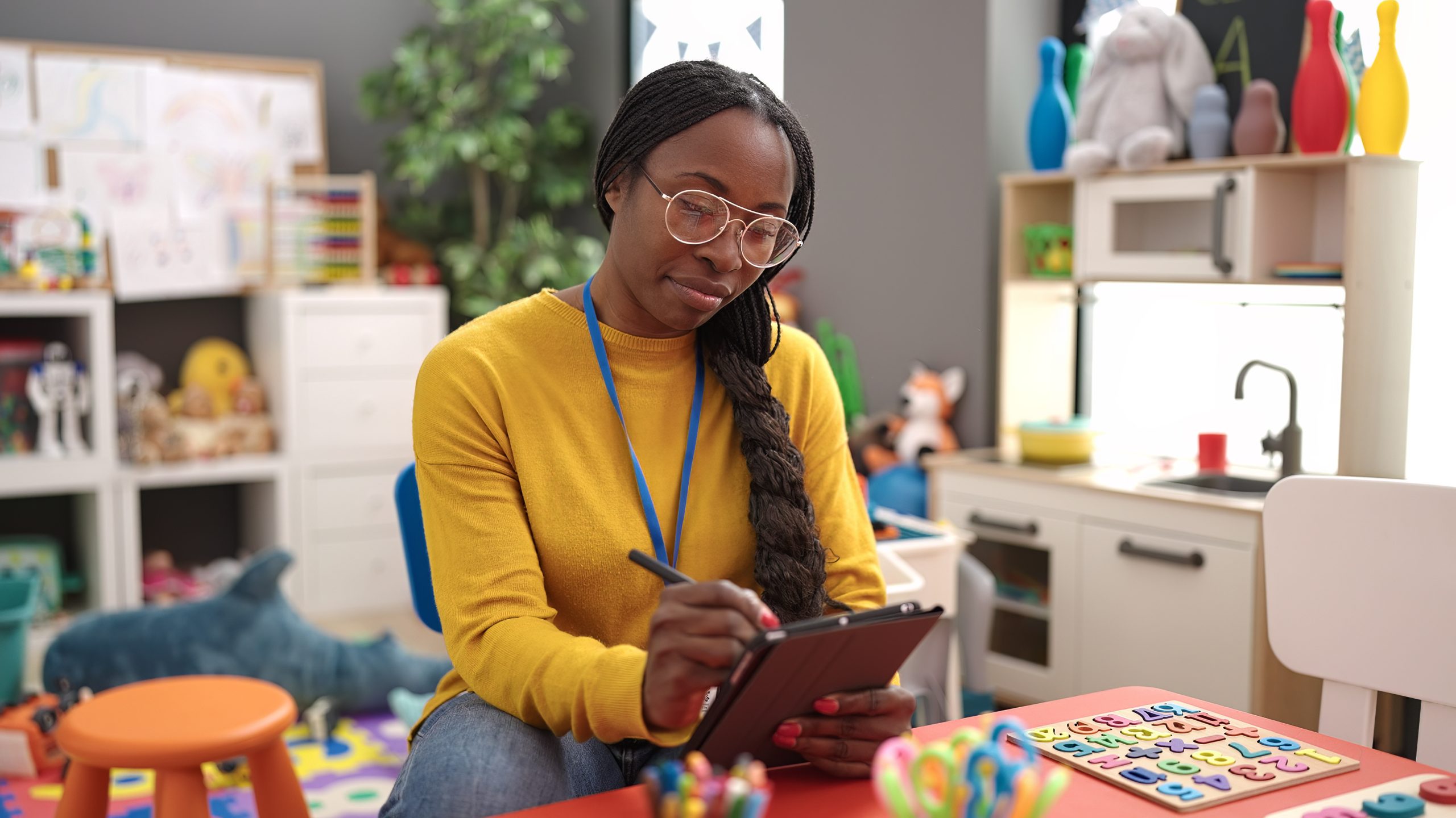 African woman working as teacher with tablet at kindergarten